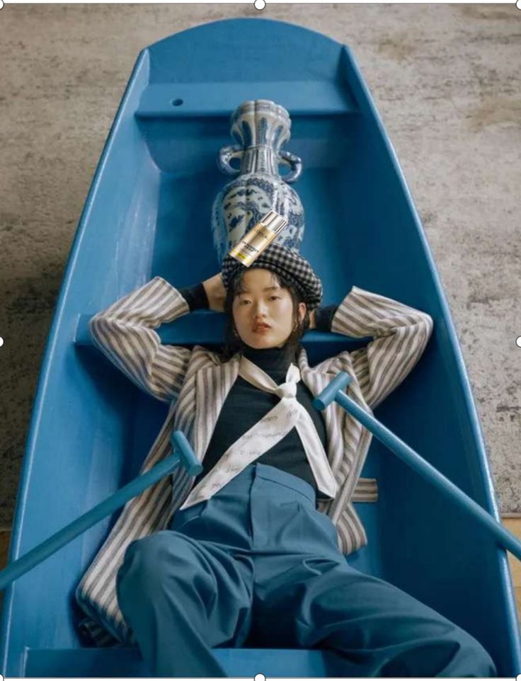 a doll is sitting in a blue boat with a hat on it's head