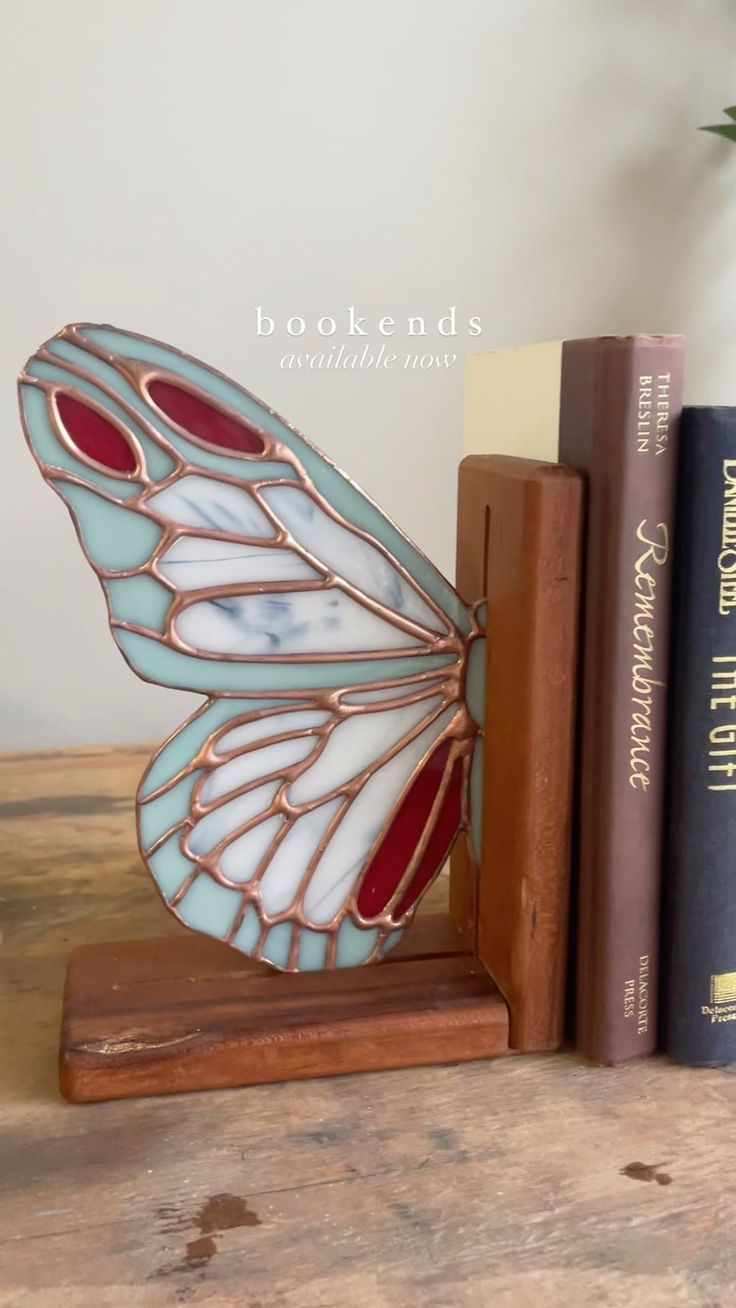 a butterfly figurine sitting on top of a book shelf next to two books