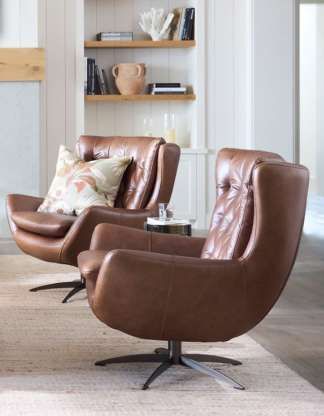 two brown leather chairs sitting on top of a rug