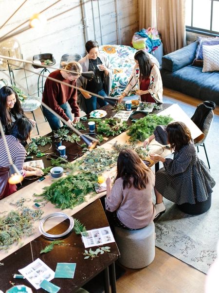 a group of people sitting around a table with plants on it and plates in front of them