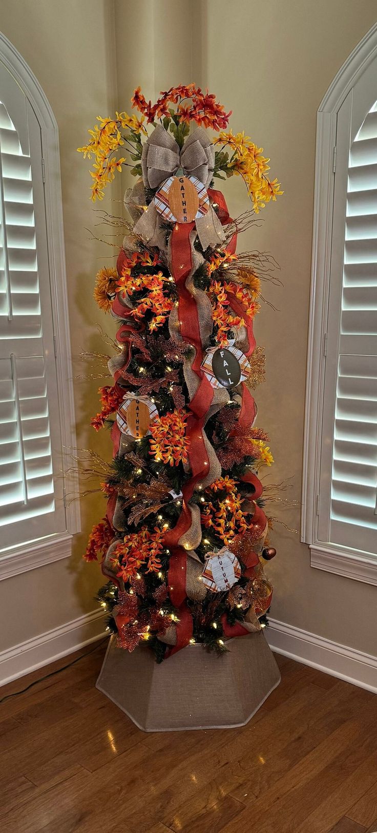 a decorated christmas tree in the corner of a room with shutters open to reveal windows