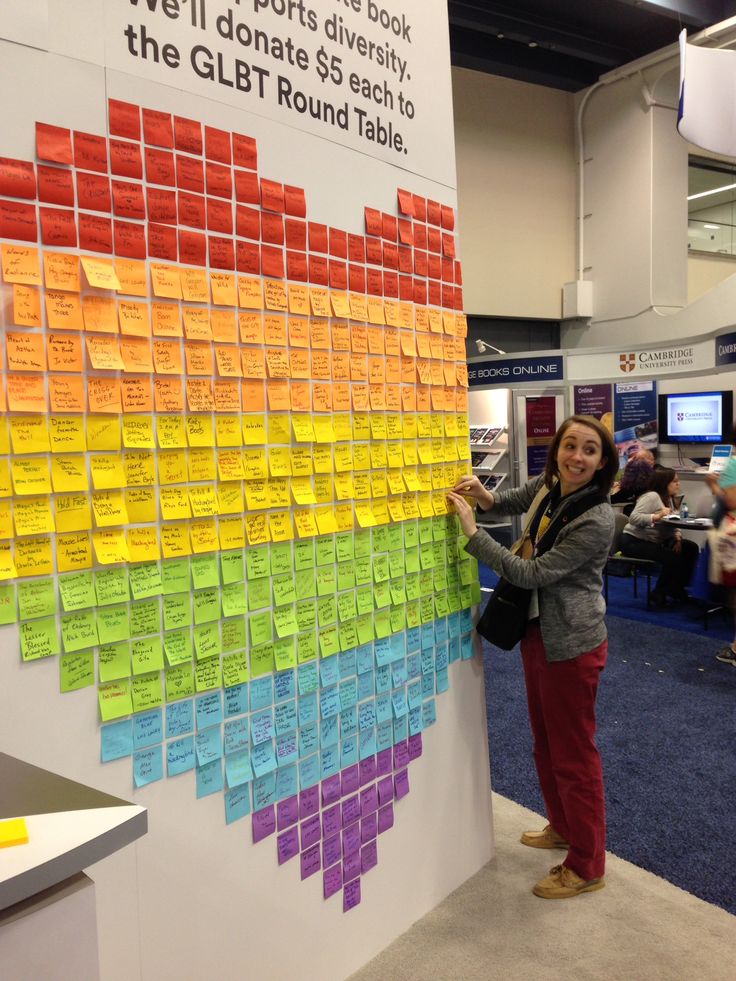 a woman standing next to a wall covered in sticky notes