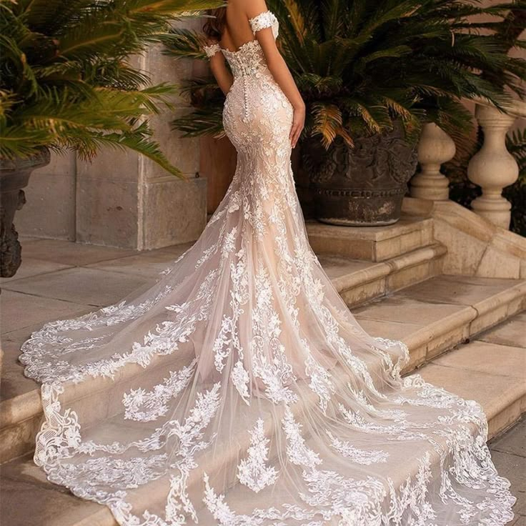 a woman in a wedding dress is standing on some steps with her back to the camera