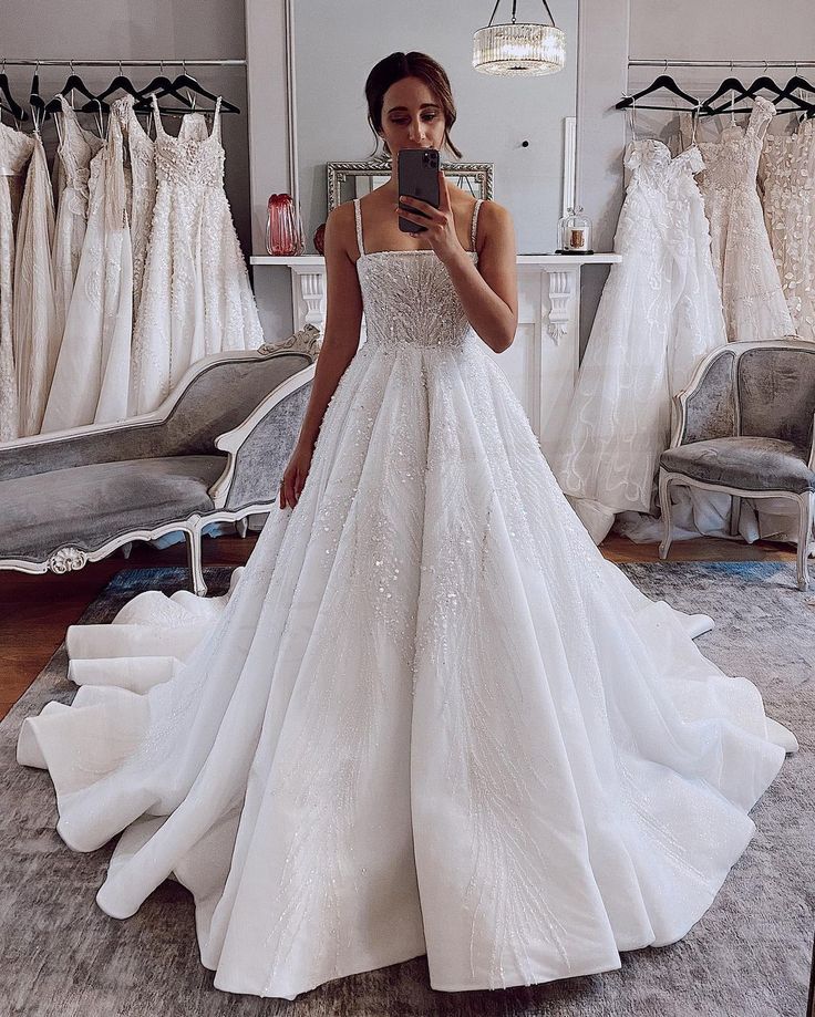 a woman taking a selfie in front of her wedding dress on the mirror while looking at it