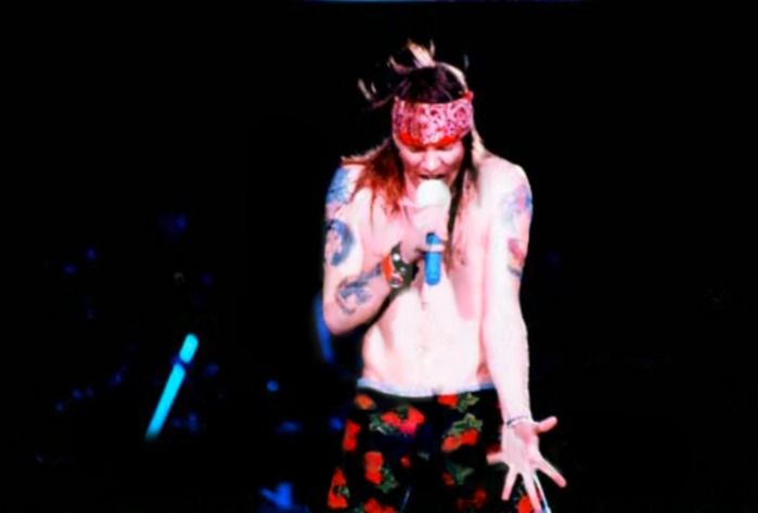 a man with long hair and tattoos standing on stage