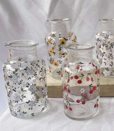 five glass vases with flowers and berries on them