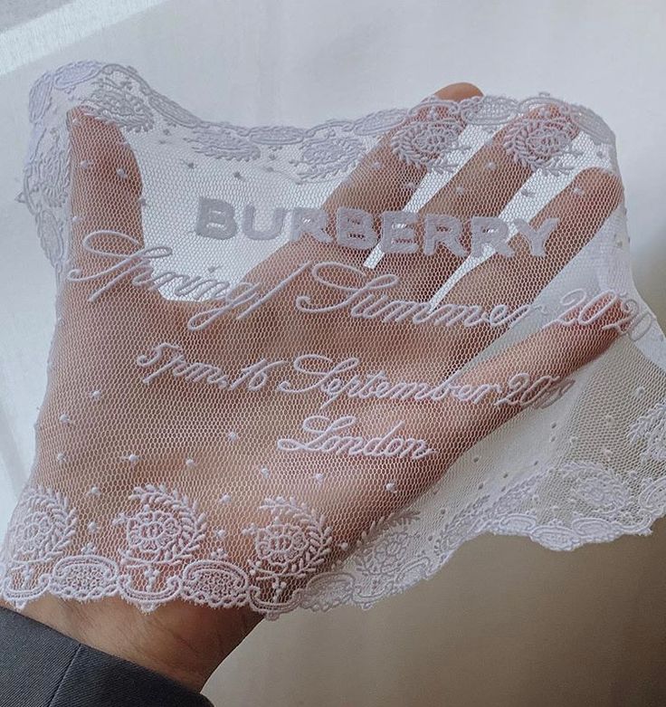 a person's hand is covered with white lace and the words burbery are written on it