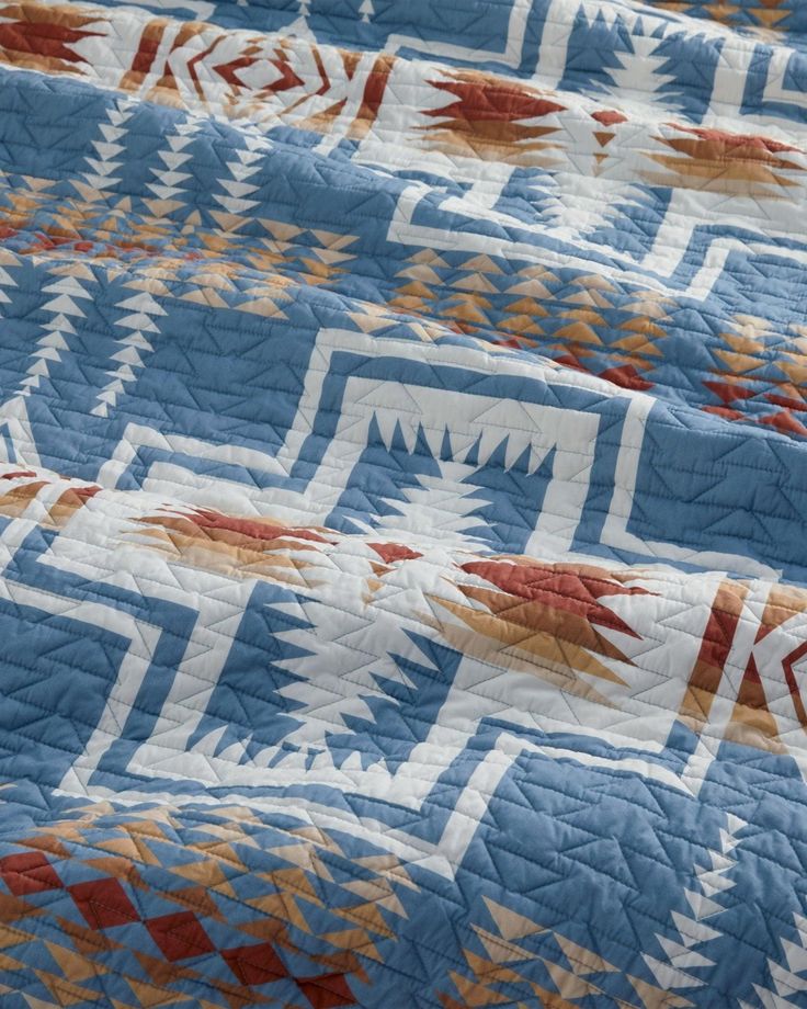 a blue quilt with orange and white designs on it