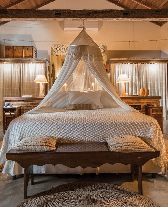 a bed with a white canopy over it in a bedroom next to two tables and lamps