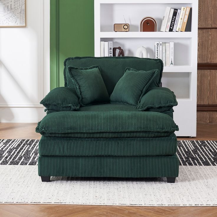 a green chair sitting on top of a rug in front of a white book shelf