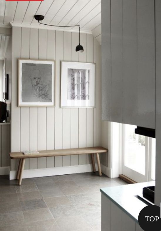 a kitchen with two pictures hanging on the wall and a bench in front of it