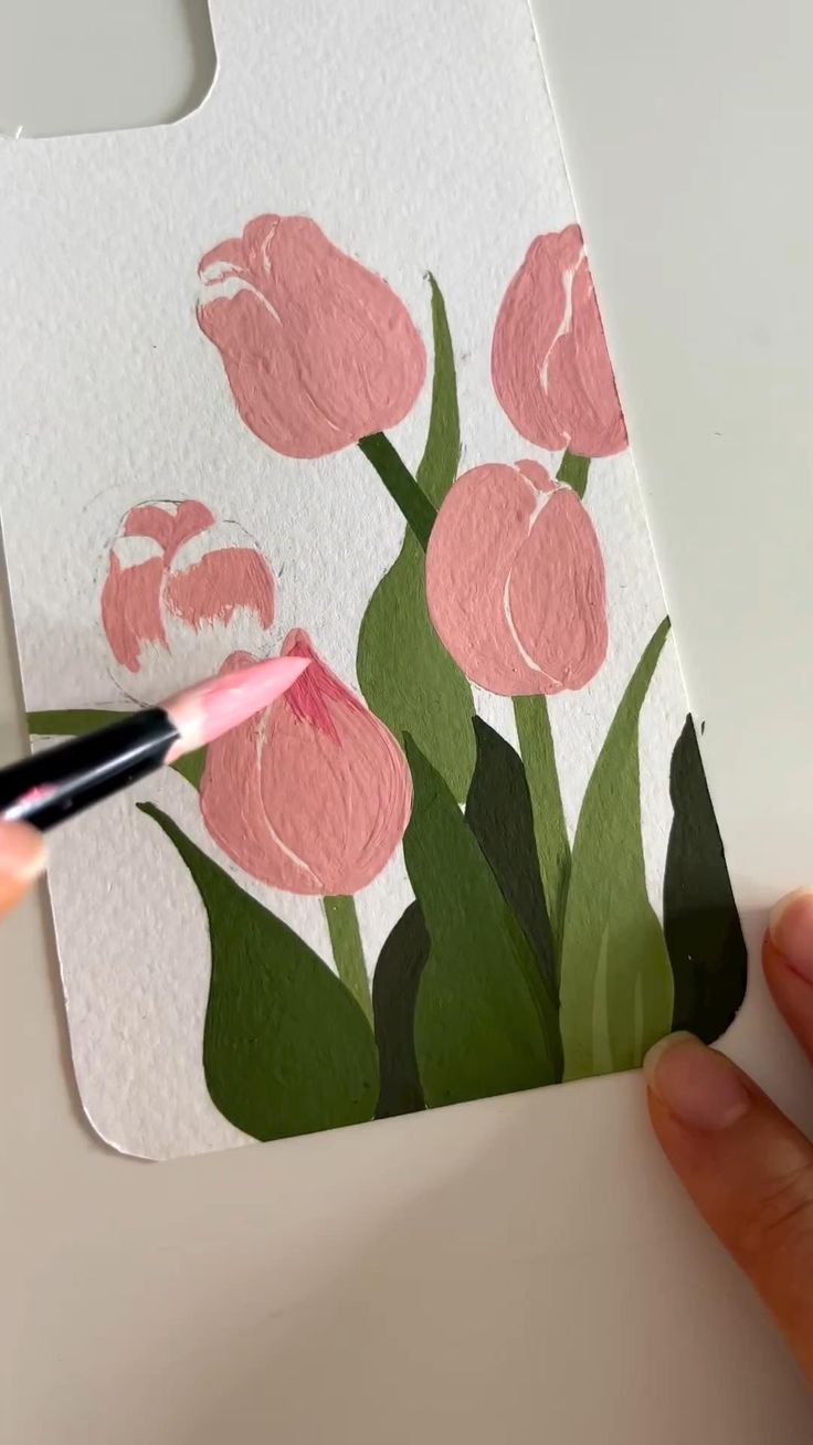 someone is painting pink flowers on a piece of paper