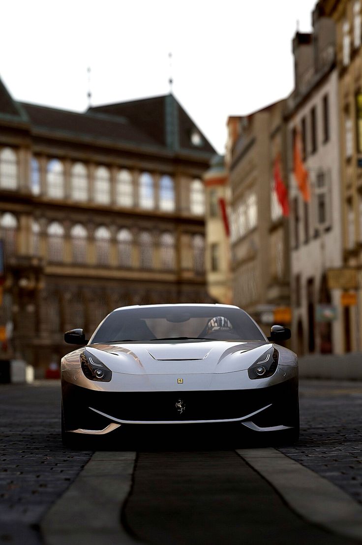 a white sports car driving down a street next to tall buildings