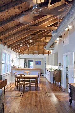 an open kitchen and dining room with wood flooring, exposed beams, and white walls