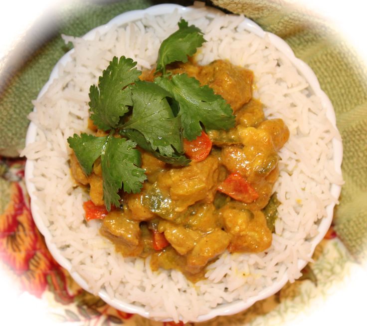 a white plate topped with rice covered in sauce and cilantro leaves on top