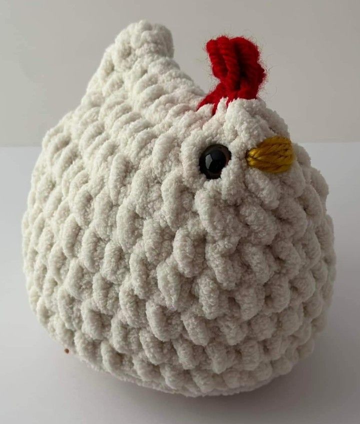 a white stuffed animal with a red bird on it's head, sitting in front of a white background