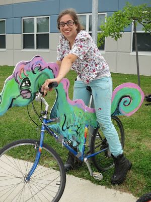 a woman riding on the back of a blue bike with a green dragon painted on it