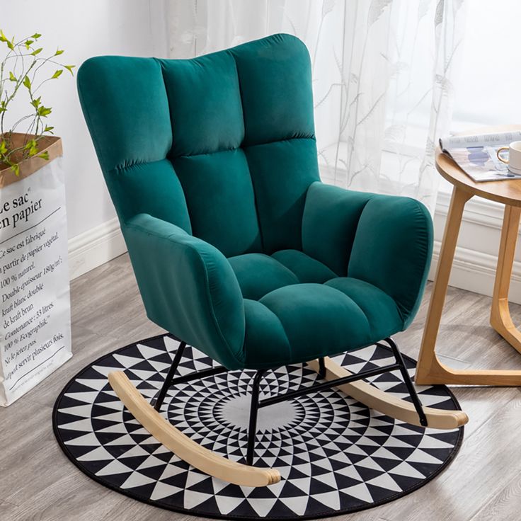 a green rocking chair sitting on top of a black and white rug next to a wooden table