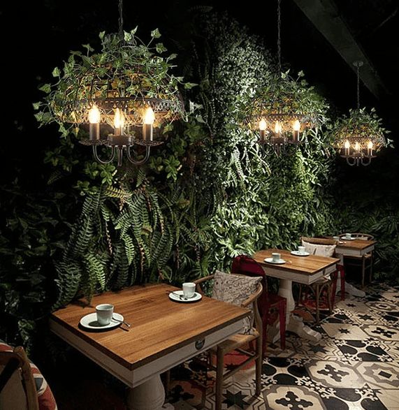 an indoor dining area with tables, chairs and hanging plants on the wall behind them