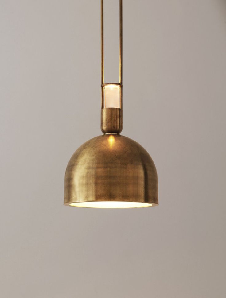 a gold colored pendant light hanging from a ceiling in a room with grey walls and flooring