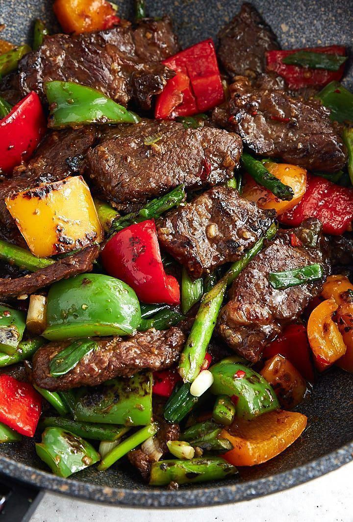 steak and peppers in a skillet on the stove