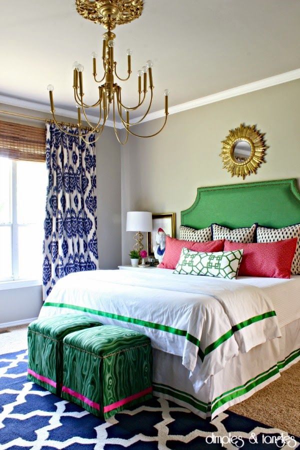 a bedroom decorated in green, white and pink with a chandelier above the bed