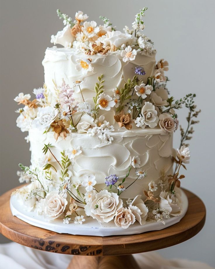 a white wedding cake decorated with flowers and greenery