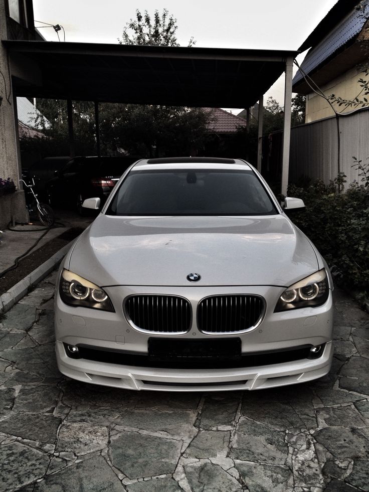 a silver car parked in front of a house on a cobblestone driveway with an awning over it