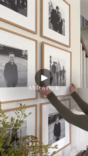 a woman is placing pictures on the wall