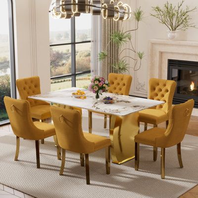 a dining room table with yellow chairs and a fire place in the corner, next to a fireplace