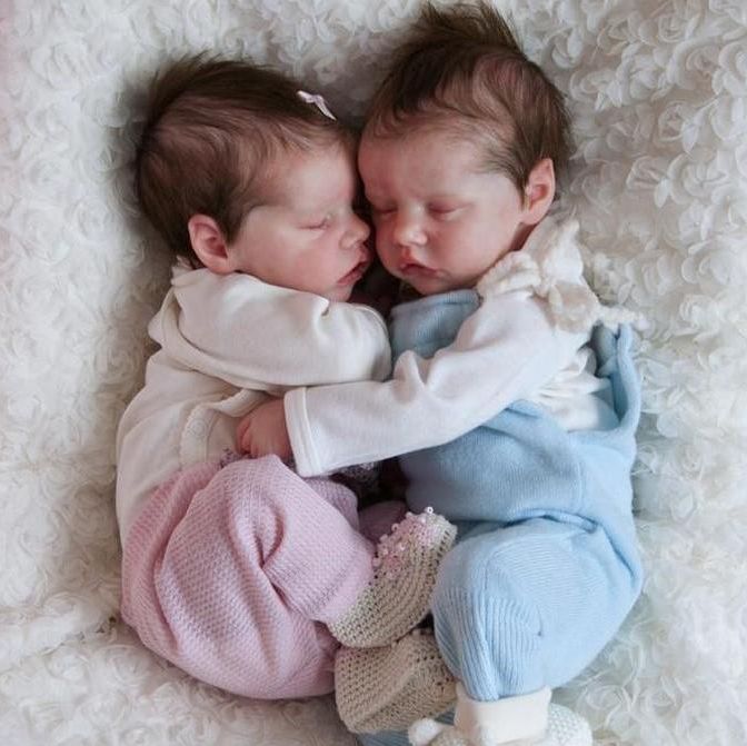 two newborn babies cuddle together on a white blanket