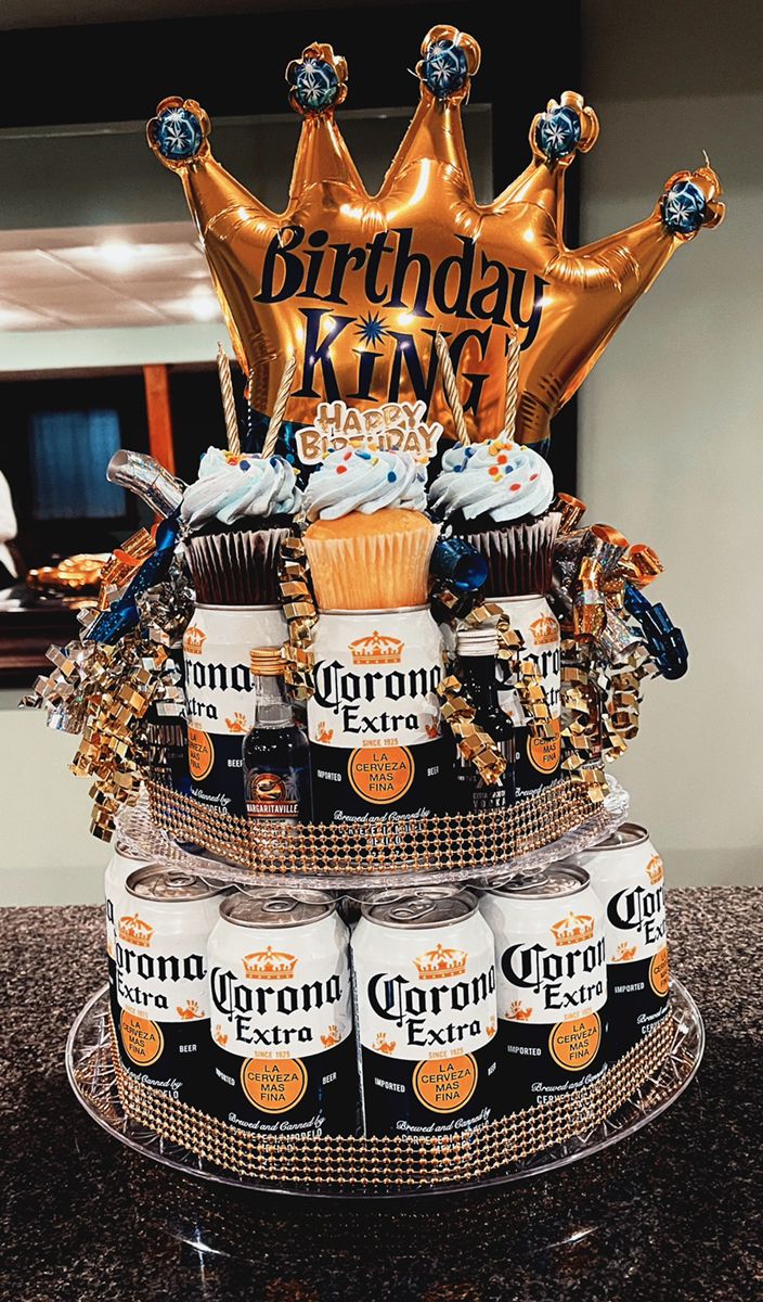 a birthday cake made out of beer cans and gold foil balloons with the words corona king on top