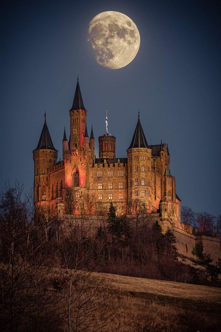 the full moon shines brightly over an old castle