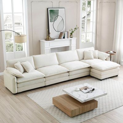 a living room with white couches and windows in the backround, along with a large rug on the floor