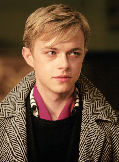 a young man with blonde hair wearing a coat