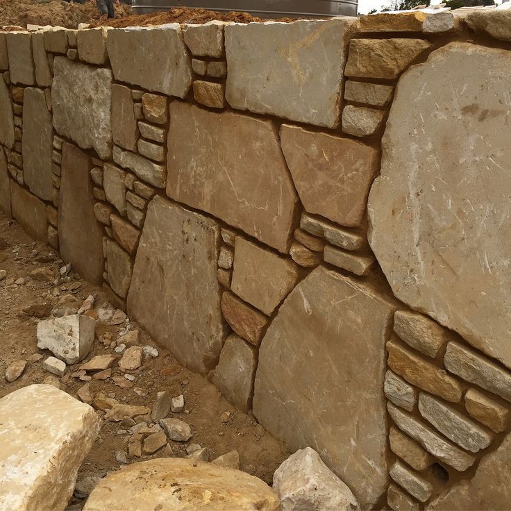 a stone wall is shown with rocks in the foreground