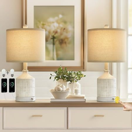 two lamps sitting on top of a dresser next to a vase with flowers in it