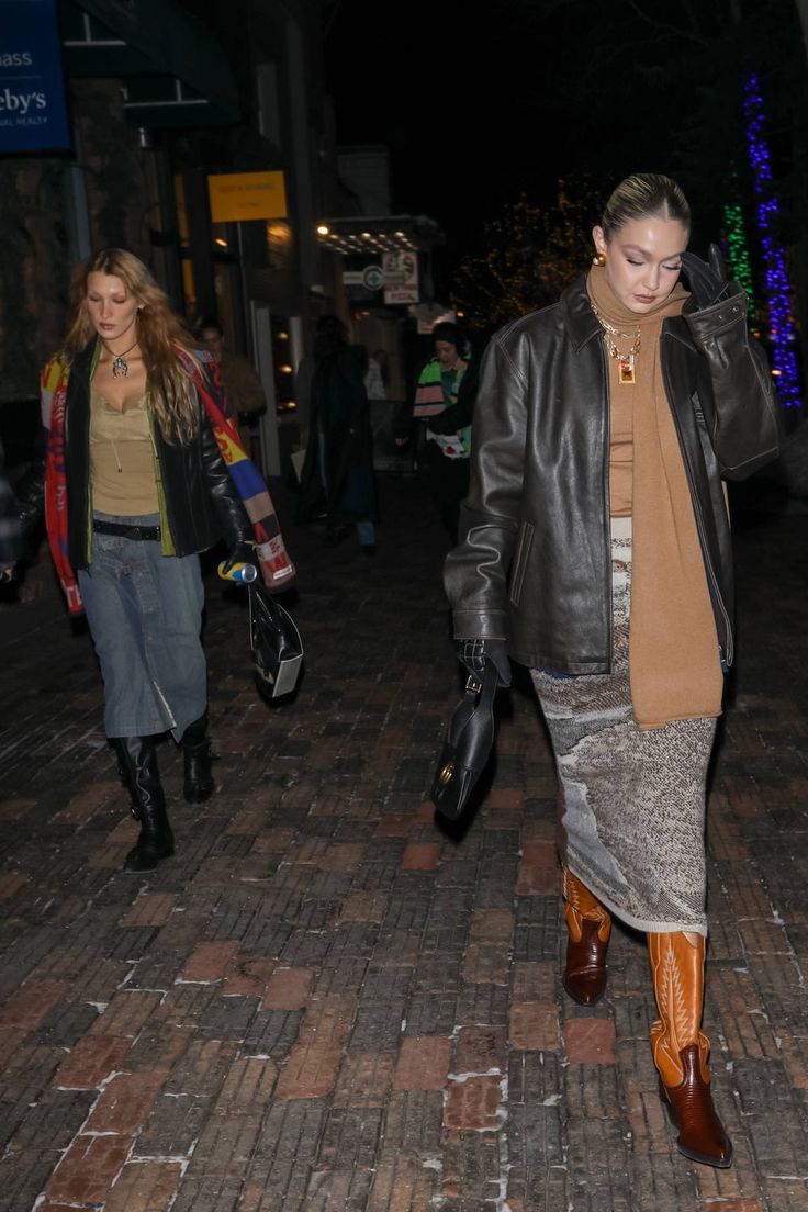 two women are walking down the street at night, one is wearing a leather jacket