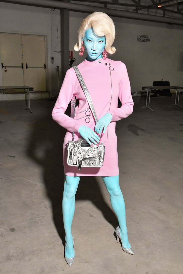 a mannequin dressed in pink and blue poses for the camera while holding a purse