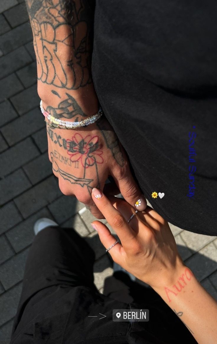 a man and woman holding hands with tattoos on their arms, both wearing matching bracelets