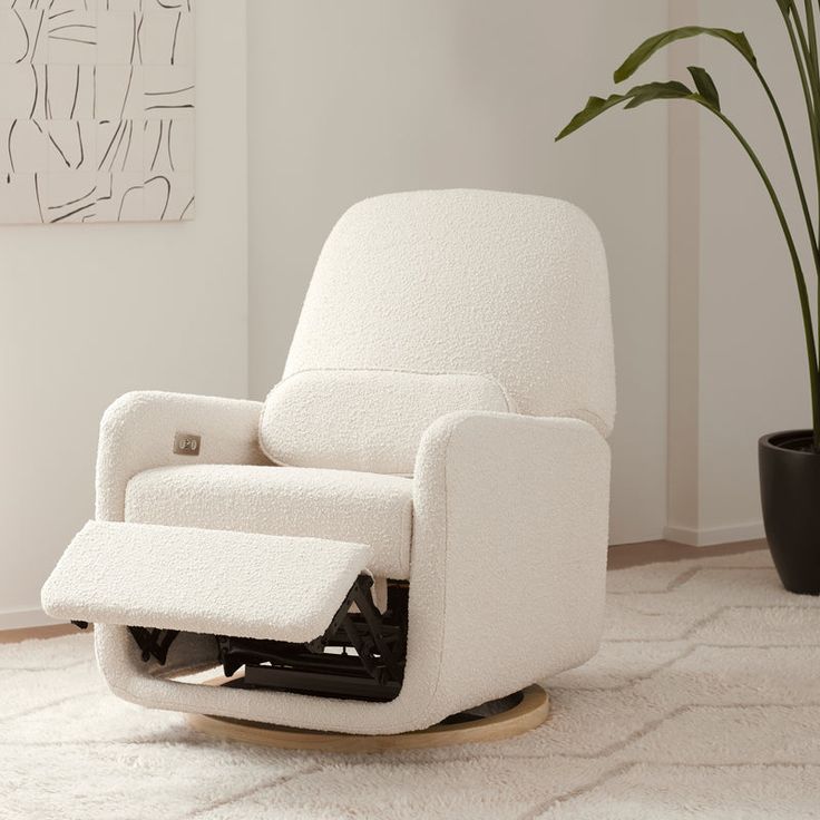 a white recliner chair sitting on top of a rug next to a potted plant