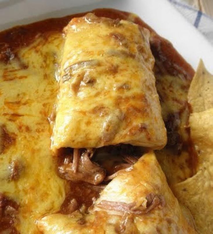 an enchilada on a plate with tortillas and chips in it