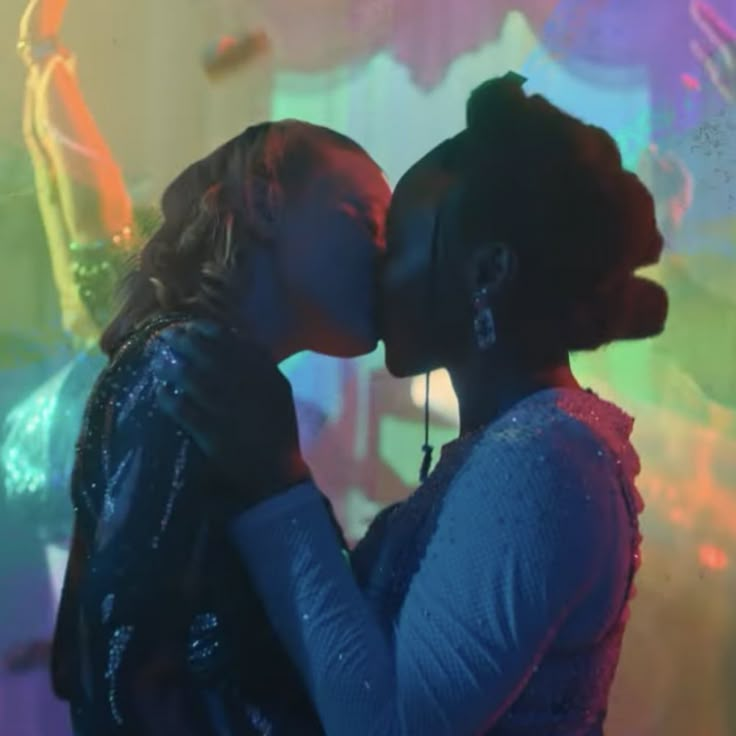 two people kissing each other in front of colorful lights