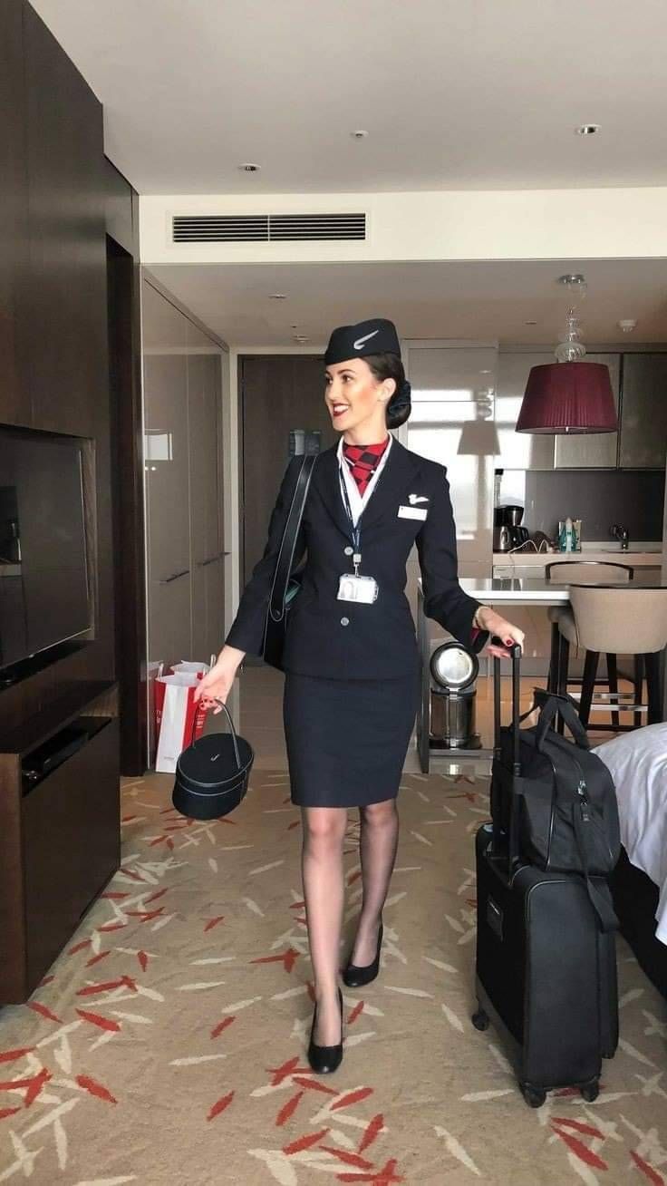 a woman in an air hostess uniform carrying luggage