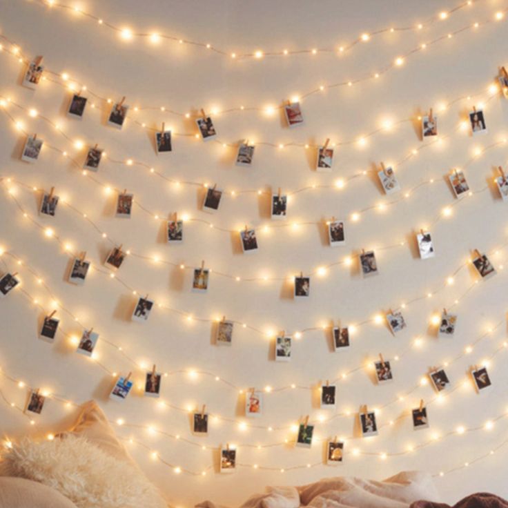 a bedroom with lights strung from the ceiling and pictures hanging on the wall above it