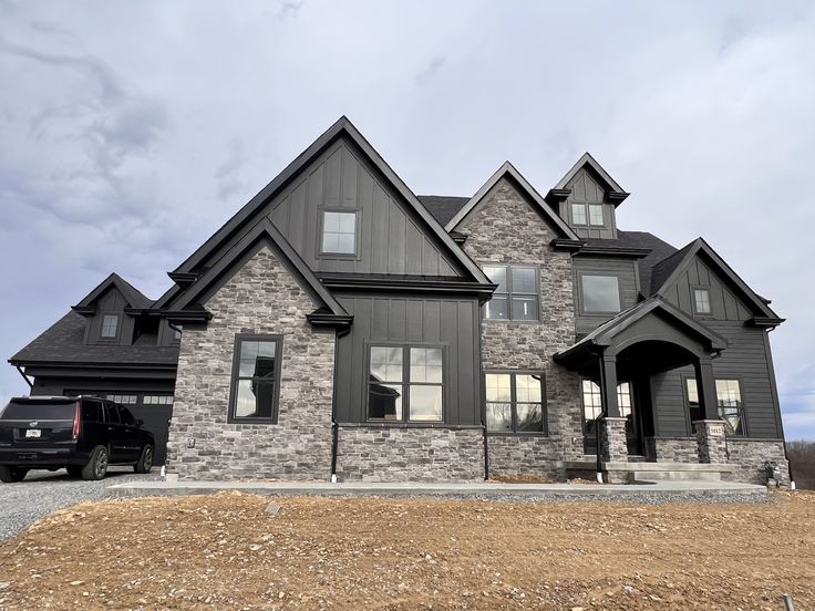 a truck is parked in front of a large house with stone and shingled roofing