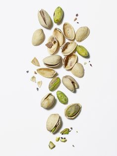 pistachio nuts are scattered on a white surface