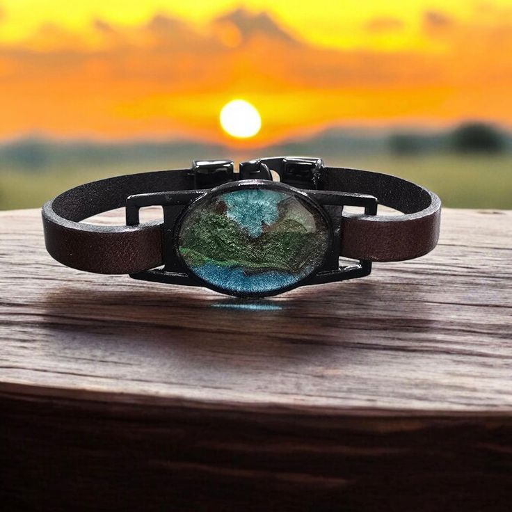 Discover the captivating beauty of our leather bracelet adorned with a teal, green, and black mountain resin centerpiece. This unique accessory combines the elegance of leather with art, creating a truly one-of-a-kind piece that supports sustainable fashion. Sold in 5 different sizes measured in inches: 7, 7.5, 8, 8.5, 9 Benefits and Features: Unique and eye-catching design High-quality leather and resin materials Adds a touch of sparkle and color to any outfit Lightweight and comfortable to wea Cork Bracelet, Black Mountain, Eco Friendly Fashion, Resin Material, Green And Black, Black Glitter, Teal Green, Accessories Unique, High Quality Leather