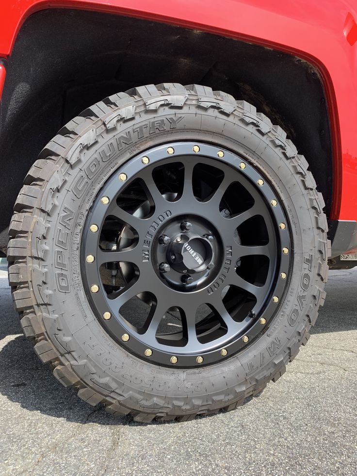 the front wheel of a red truck with black spokes and tire hubs on it