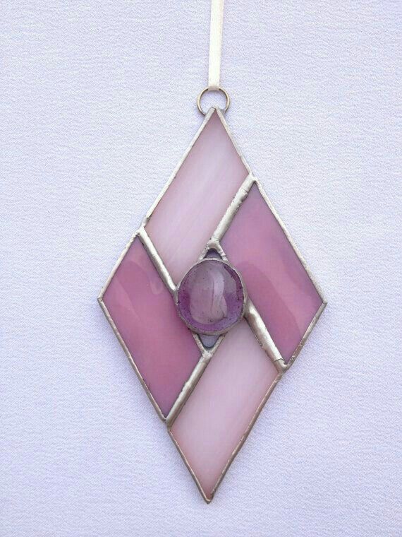 a pink and white square shaped pendant with a purple bead on it's end